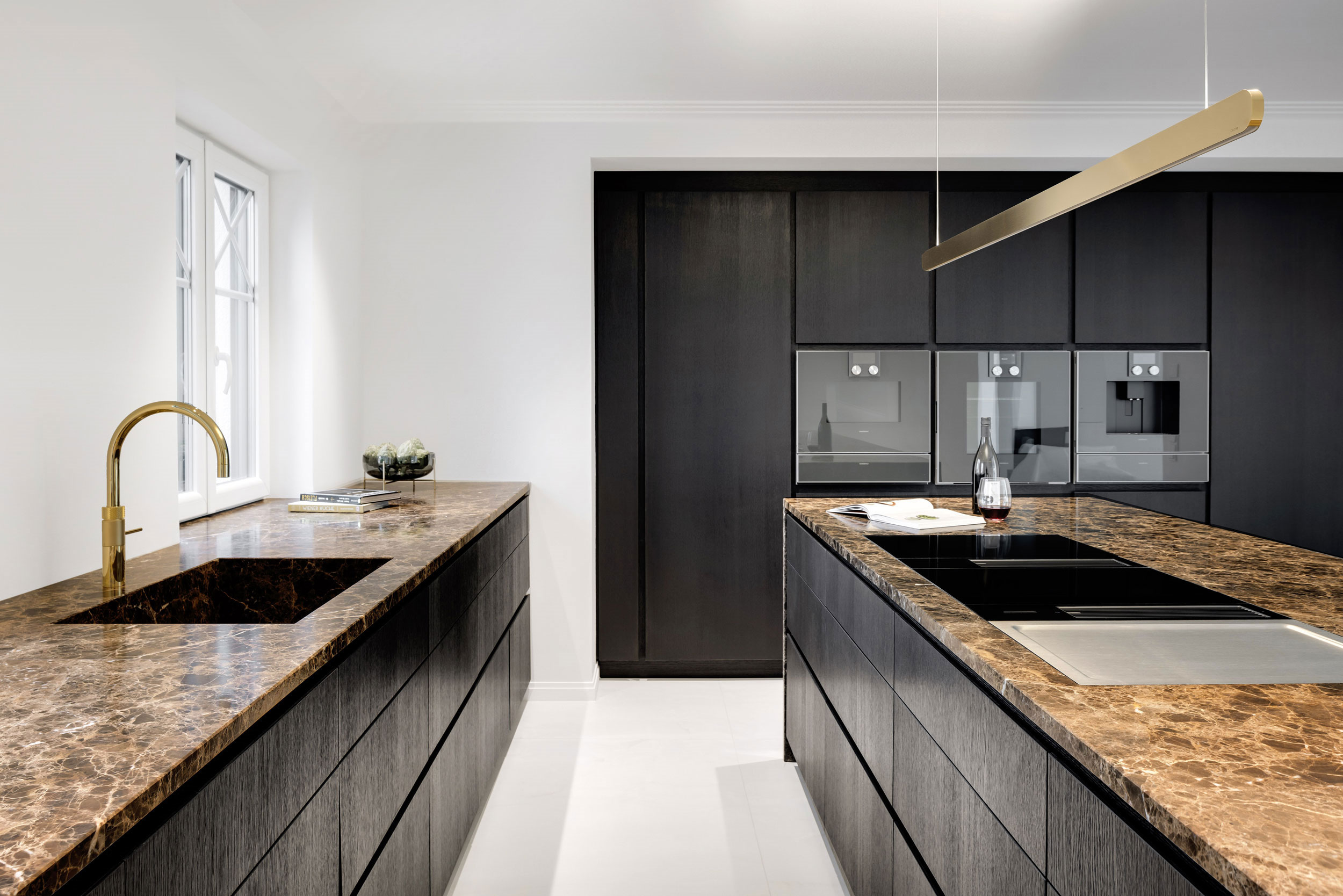 GENUSS-WERKSTATT Küche aus braunschwarz pigmentierter Eiche, grifflose Fronten, hellem Stein und Messing