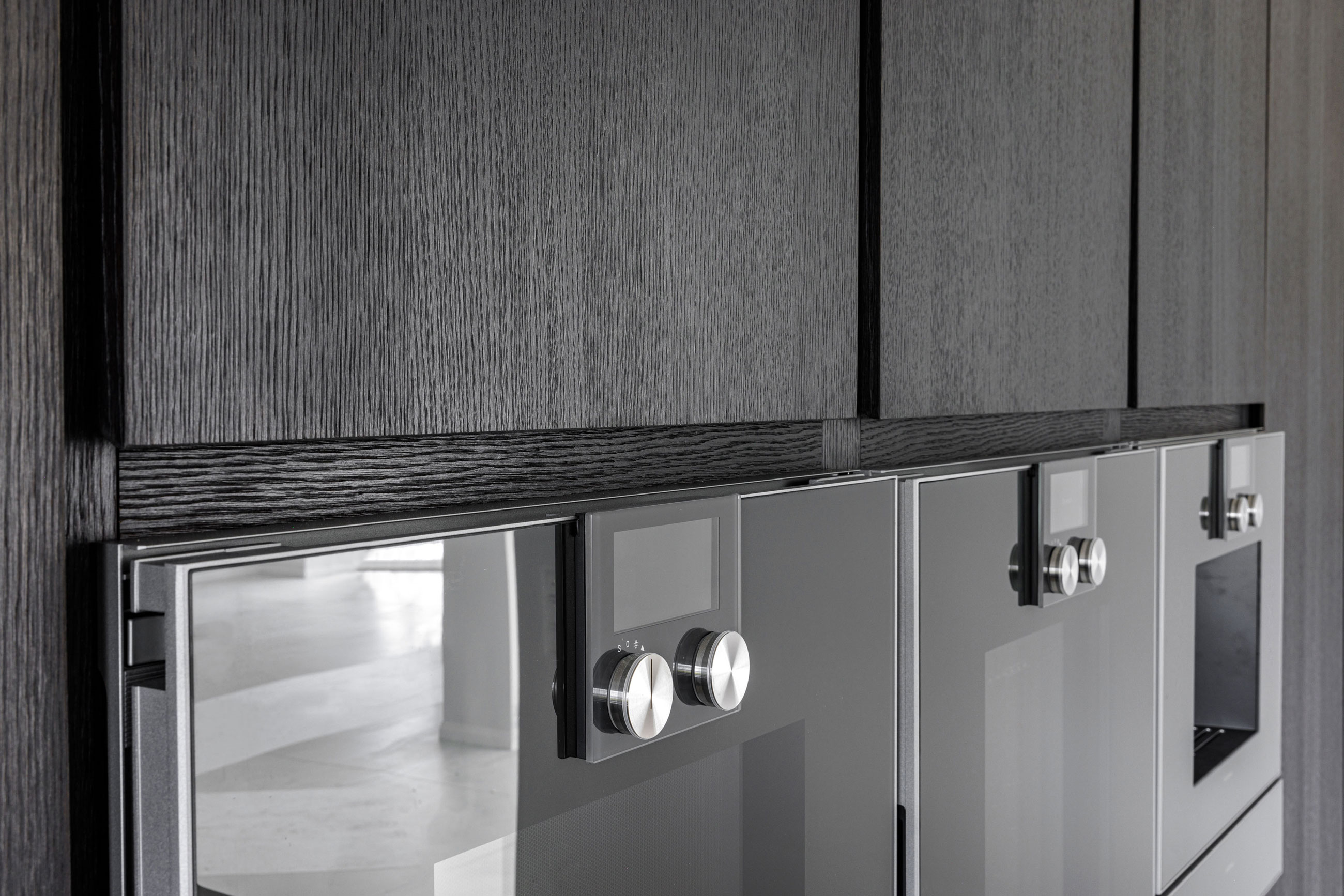 Küche aus braunschwarz pigmentierter Eiche, grifflose Fronten, hellem Stein und Messing von Robby Hoffman Möbelsdesign